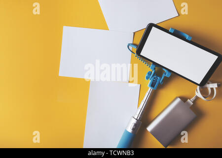 Mise à plat avec un monopode et smartphone photos sur un fond jaune. Concept voyages d'été. Banque D'Images