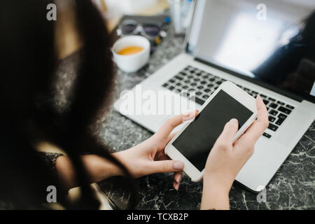 Jeune femme freelance travail à domicile. Défilement de l'écran du smartphone. Banque D'Images