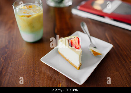 Un délicieux morceau de gâteau aéré avec fraise sur le dessus. Frappe à froid à côté. Banque D'Images