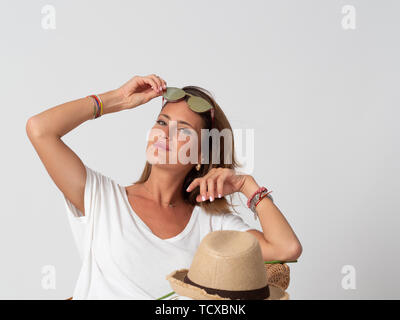 Jeune femme blonde pose avec des lunettes devant un fond blanc Banque D'Images