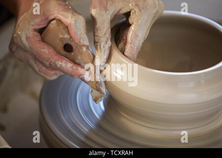 Close up of female hands shaping clay sur potters wheel tout en travaillant en studio, copy space Banque D'Images