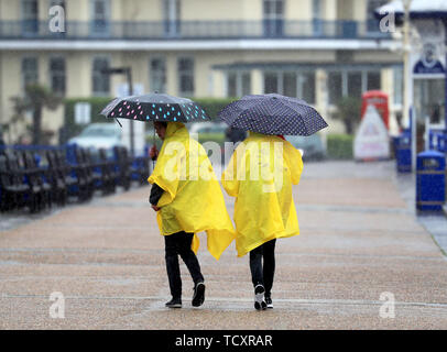 Deux étudiants d'échange allemand brave la pluie torrentielle sur la promenade, à Eastbourne, dans le Sussex, comme le prédit la pluie balaie le sud-est. Banque D'Images