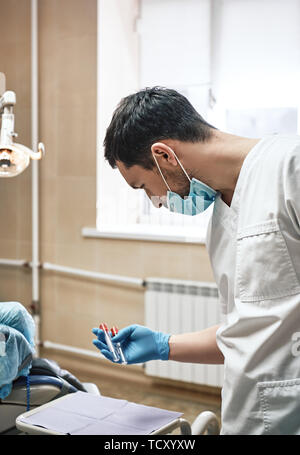 Portrait des hommes portant des uniformes blancs dentiste préparation au traitement en cabinet dentaire. Équipement médical moderne. Banque D'Images