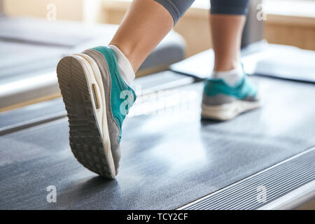 Entraînement cardio. Photo recadrée de la femme dans les chaussures de sports d'exécution sur tapis roulant à la salle de sport. Concept Sport et fitness Banque D'Images