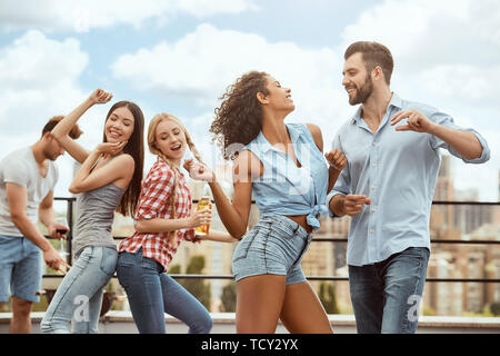 Let's dance ! Groupe de professionnels et de jeunes sont sont la danse et s'amuser tout en ayant un barbecue sur le toit. Concept de barbecue. L'heure d'été Banque D'Images