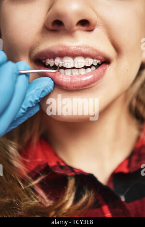 Close-up of girl ouvrant la bouche toute grande lors de l'inspection de la cavité orale. Dentiste est contrôler les dents avec l'aide de supports d'outils de dentiste. Une médecine Banque D'Images