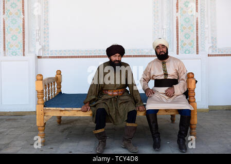 Kokand, vallée de Ferghana, en Ouzbékistan - 4 juin 2019 : les hommes, habillés en ouzbek dans le turban traditionnel, assis sur le banc dans le palais de Khuda Banque D'Images