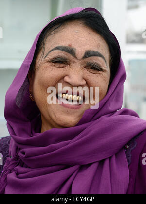 Marguilan, vallée de Ferghana, en Ouzbékistan - 2 juin 2019 : Portrait de la femme ouzbèke rire, habillés dans l'écharpe, avec l'incroyable composition de l'e Banque D'Images