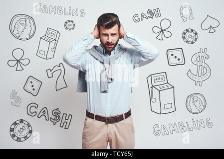 Je ne veux pas vous entendre ! Close-up portrait of young man ennuyé les oreilles de clôture avec les mains en position debout contre l'arrière-plan gris avec différentes doodle Banque D'Images