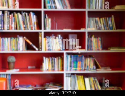 Étagère rouge floue avec de nombreux livres dans la bibliothèque de l'éducation contexte Concept. Banque D'Images