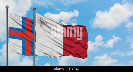 Îles Féroé et de brandir le drapeau de Malte dans le vent contre ciel bleu nuageux blanc ensemble. Concept de diplomatie, de relations internationales. Banque D'Images