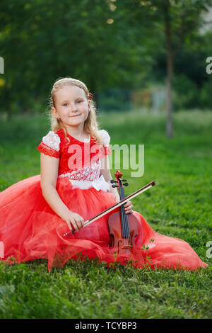 Heureux fille joue du violon dans parc d'été Banque D'Images