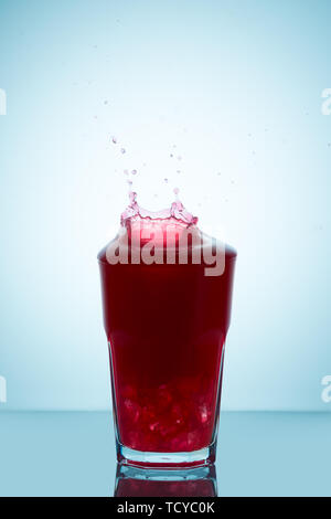 Splash sur un verre de jus de framboises représentant le concept d'une chute sans déversement Banque D'Images