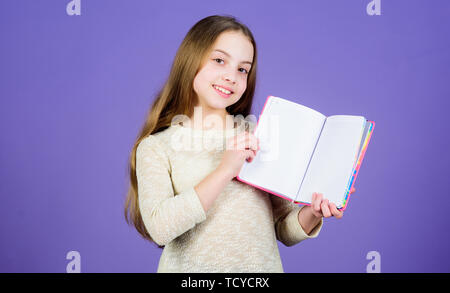 L'application de son livre à la connaissance du monde réel. Adorable petite fille tenant un livre ouvert. Enfant mignon petit livre avec la connaissance dans les mains. Compétences Connaissances. Jour des connaissances ou le 1 septembre, l'espace de copie. Banque D'Images