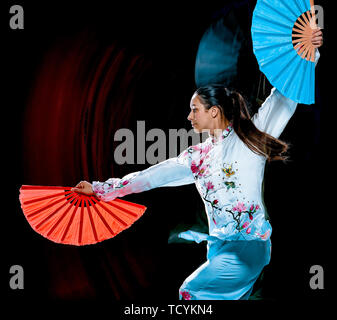 Une femme chinoise Tai Chi Chuan partacticing Tadjiquan posture studio shot isolé sur fond noir avec effet light painting Banque D'Images