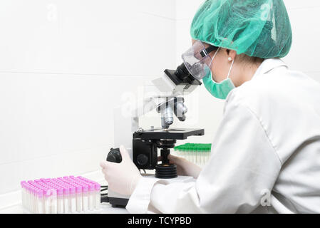 Jeune femme scientifique dans un laboratoire moderne, à l'aide de microscope . Banque D'Images