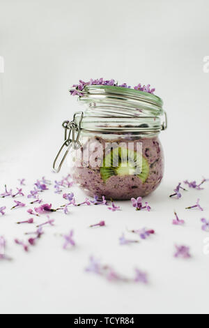 Petit déjeuner smoothie sain dans un bocal en verre avec fleurs lilas sur fond blanc Banque D'Images