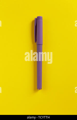 Stylo violet sur fond de papier jaune. Le centre de la composition. Des couleurs contrastées. Retour à l'école, l'éducation concept. Vue d'en haut. Mise à plat. La verticale. Un minimum de Banque D'Images