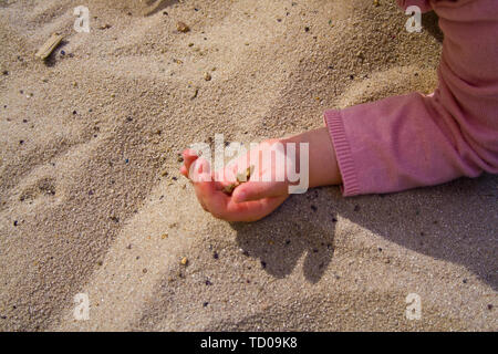 Les mains dans le sable tout en jouant. Banque D'Images