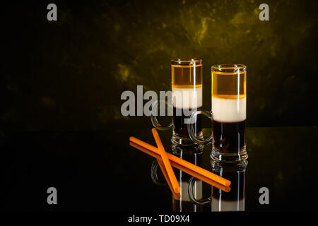 Deux cocktails B-52 abattu avec paille sur noir surface de miroir et wall background Banque D'Images