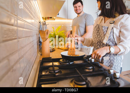 Couple cooking ensemble à la cuisine. faire frire les crêpes orange coupe Banque D'Images