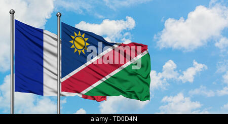 La France et la Namibie drapeaux dans le vent contre ciel bleu nuageux blanc ensemble. Concept de diplomatie, de relations internationales. Banque D'Images