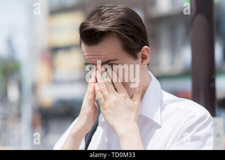 Un jeune homme a des démangeaisons, larmoiement des yeux gonflés, à cause de l'allergie au pollen Banque D'Images