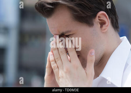 Un jeune homme a des démangeaisons, larmoiement des yeux gonflés, à cause de l'allergie au pollen Banque D'Images