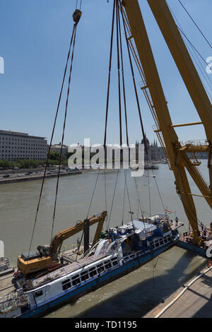 Budapest, Hongrie. 11 Juin, 2019. Photo prise le 11 juin 2019 montre l'épave du bateau de tourisme Hableany (sirène) soit portée à la surface de la rivière au centre-ville de Budapest, Hongrie. Les autorités hongroises a introduit le bateau de tourisme Hableany (Sirène) qui a coulé le 29 mai à la surface, avec quatre victimes trouvés piégés à l'intérieur de l'épave, selon des sources officielles ici mardi. Credit : Attila Volgyi/Xinhua/Alamy Live News Banque D'Images