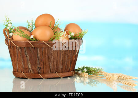 Oeufs dans le panier sur fond bleu naturel Banque D'Images