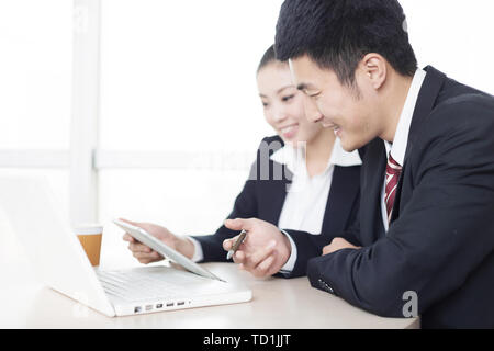 Bel homme d'affaires chinois et jolie chinese businesswoman with digital tablet in modern office Banque D'Images