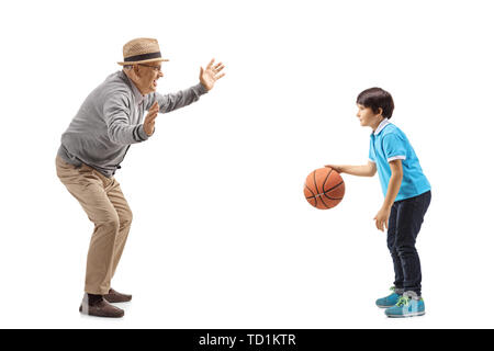 Toute la longueur de balle grand-père jouant au basket-ball avec son petit-fils isolé sur fond blanc Banque D'Images