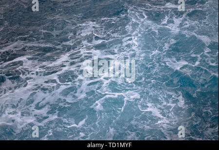 Les vagues de l'océan bleu blanc créant des tourbillons mousseux vu de dessus. Banque D'Images