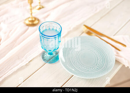 Le tableau pour les clients, décoré avec des bougies, servis avec des couverts et de la vaisselle et couverts d'une nappe plaque bleue et or rose sur fourchette et couteau Banque D'Images