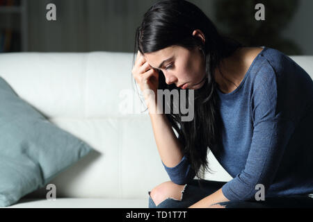 Worried woman thinking seul assis sur un canapé dans la nuit à la maison Banque D'Images