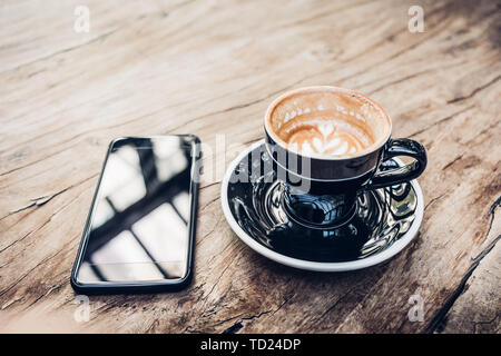 Close up sex black tasse à café et mobile sur table en bois près de la fenêtre avec la lumière solaire à cafe restaurant.vie Loisirs.Nourriture et boisson Banque D'Images
