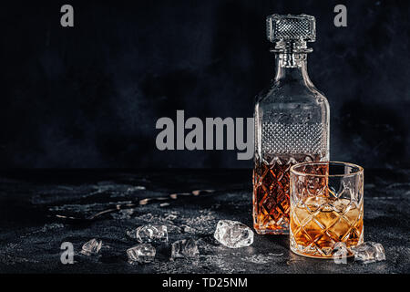 Le verre de whisky avec un carré carafe sur une pierre noire. Banque D'Images