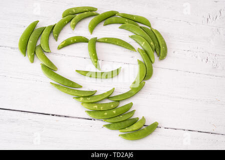 Un tas de pois sugar snap vert écossais dans un comique sur un visage en forme de planches en bois blanc. Une bonne image pour l'épicier vert ou d'épicerie fine Banque D'Images