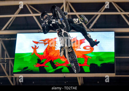 Une moto rider sauts tire un truc en face d'une image de la Welsh flag lors du lancement des Jeux mondiaux de la Nitro freestyle motor cross à la Principauté Stadium de Cardiff, comme il a été annoncé que monde Nitro Jeux auront lieu au Pays de Galles en 2020. Banque D'Images