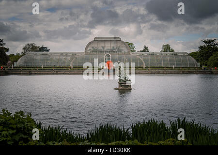Le point de vue de la Palm House à partir de l'autre côté de l'eau à Kew Gardens avec la sculpture en verre soufflé été Soleil par Dale Chihuly en face d'elle. Banque D'Images