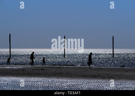 Silhouettes de personnes marchant sur une belle plage à Sankt Peter-Ording situé dans le nord de l'Allemagne Banque D'Images