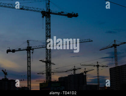 Groupe de grues de construction les bâtiments avec le Ciel de coucher du soleil sur l'arrière-plan Banque D'Images