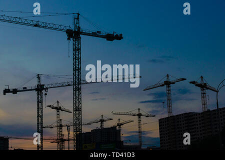 Groupe de grues de construction les bâtiments avec le Ciel de coucher du soleil sur l'arrière-plan Banque D'Images