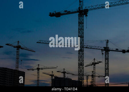 Groupe de grues de construction les bâtiments avec le Ciel de coucher du soleil sur l'arrière-plan Banque D'Images