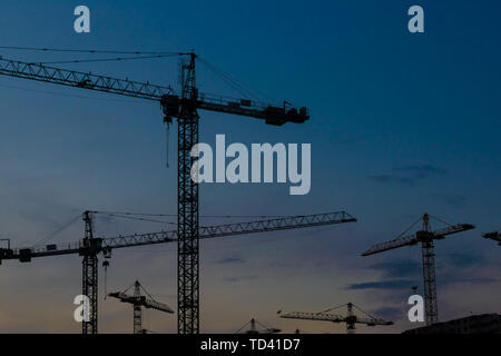 Groupe de grues de construction les bâtiments avec le Ciel de coucher du soleil sur l'arrière-plan Banque D'Images