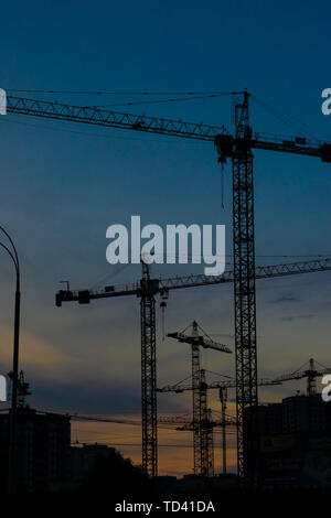 Groupe de grues de construction les bâtiments avec le Ciel de coucher du soleil sur l'arrière-plan Banque D'Images