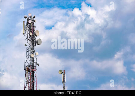 Tour de télécommunication avec beaucoup d'antennes et d'antennes montées sur fond de ciel nuageux contre elle Banque D'Images