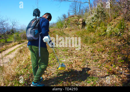 Jeune homme immergé dans la nature se consacre à sa passion, à la recherche de trésors cachés dans la forêt avec son détecteur de métal Banque D'Images