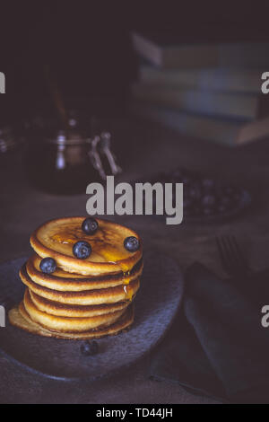 Des pancakes avec du sirop d'érable biologique et de baies sur fond sombre Petit-déjeuner américain classique Banque D'Images