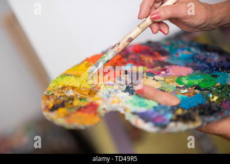 Des couleurs différentes. Close up de gouache lumineux de différentes couleurs sur palette de couleurs dans les mains de l'artiste Banque D'Images